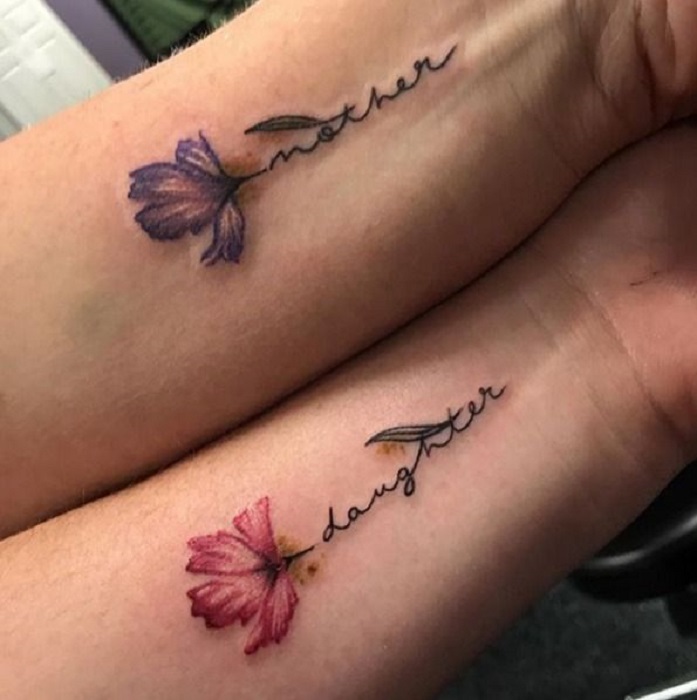 Tatuaje de madre e hija de flores y en el tallo una palabra