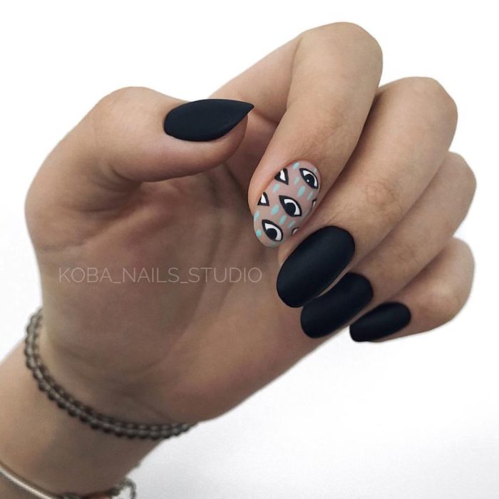 Manicura en color negro con efecto mate y un diseño de ojos en el dedo índice