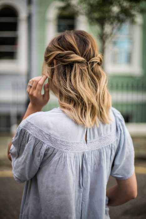 Chica de cabello corto recogido en una media coleta con torciditos a los lados