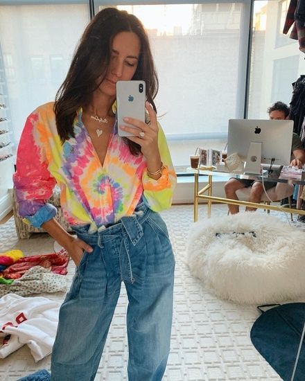 Chica se toma selfie en su habitación con jeans y una playera con efecto tie dye
