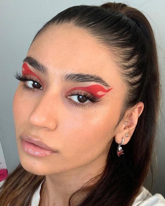 Chica morena de pelo recogido con maquillaje de flamas rojas en los ojos
