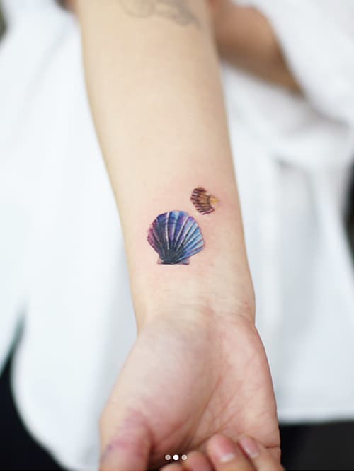Chica con un tatuaje en forma de concha de mar con un pez