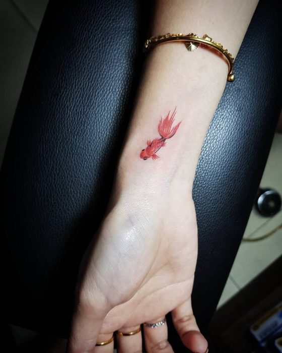 Chica con un tatuaje en forma de pez de color naranja