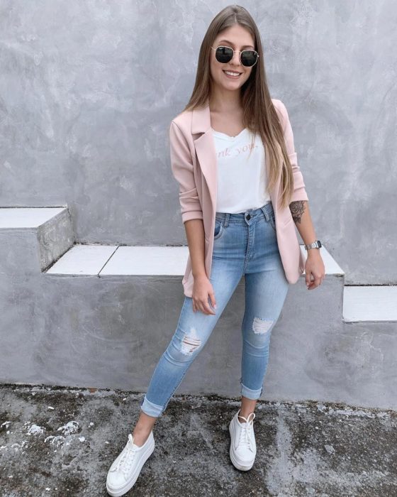 Chica usando skinny jeans, tenis blancos, blazer rosa y camisa blanca