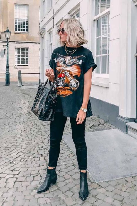 Chica usando skinny jeans y camiseta de rock con botines