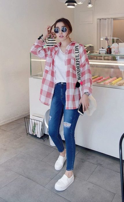 Chica usando skinny jeans con camisa blanca y camiseta de cuadros