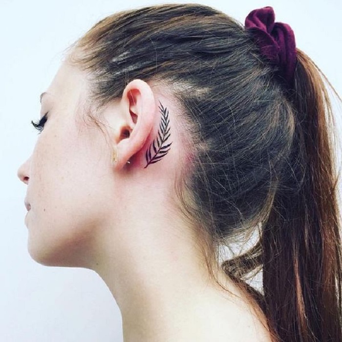 Tatuaje detrás de la oreja de una hoja de palmera