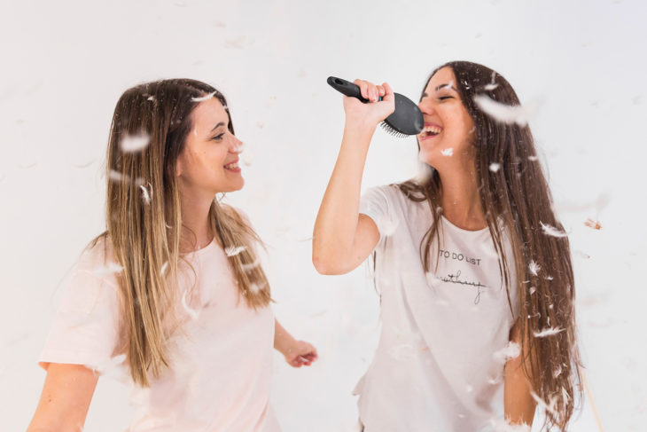 Chicas improvisando un karaoke en casa