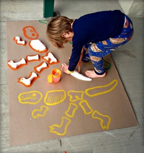 Niño descubriendo fósiles de dinosaurio hechos con papel