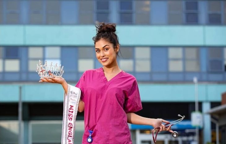 Bhasha Mukherjee en uniforme de médico, con su corona y banda de Miss Inglaterra