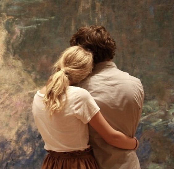 Pareja abrazándose mientras ven pintura