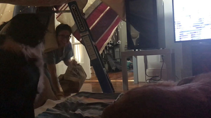 Chica entrando a una casa improvisada con cobijas viejas