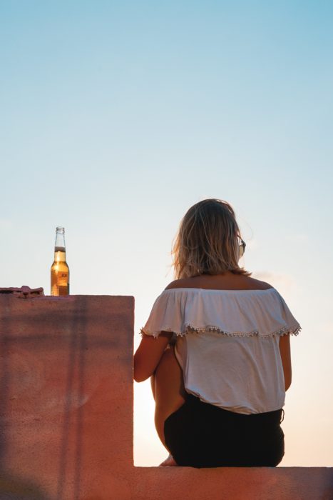 Chica sentada de espaldas y una cerveza en la barra