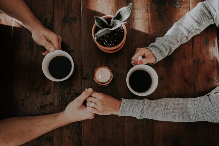 Pareja de novios tomados de la mano tomando café