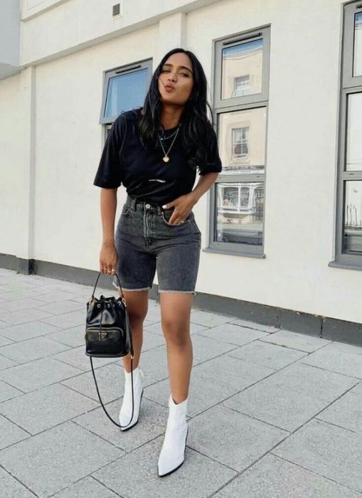 Chica con bermudas de mezclilla, blusa negra y botines blancos