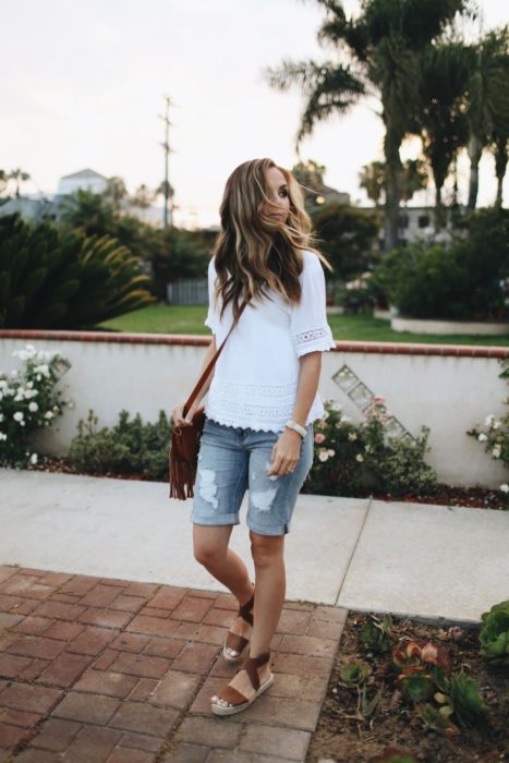 Chica con bermudas de mezclilla, blusa blanca y sandalias