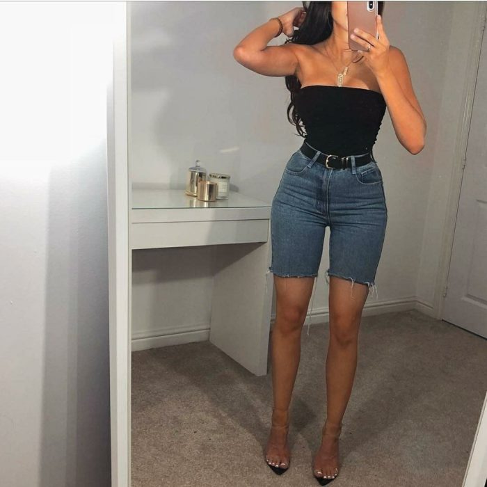 Chica con bermudas de mezclilla, top negro y sandalias transparentes
