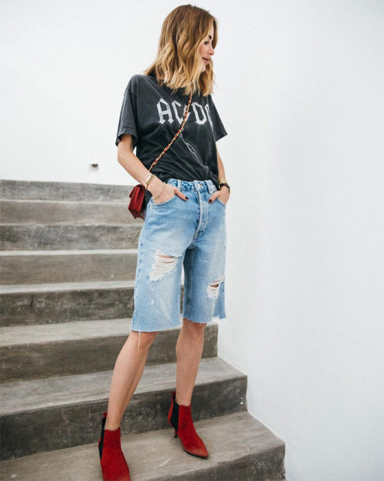 Chica con bermudas de mezclilla, camisa rockera negra y botines rojos