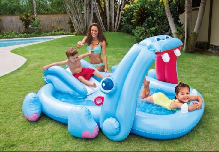 Mujer jugando con sus hijos en una alberca inflable