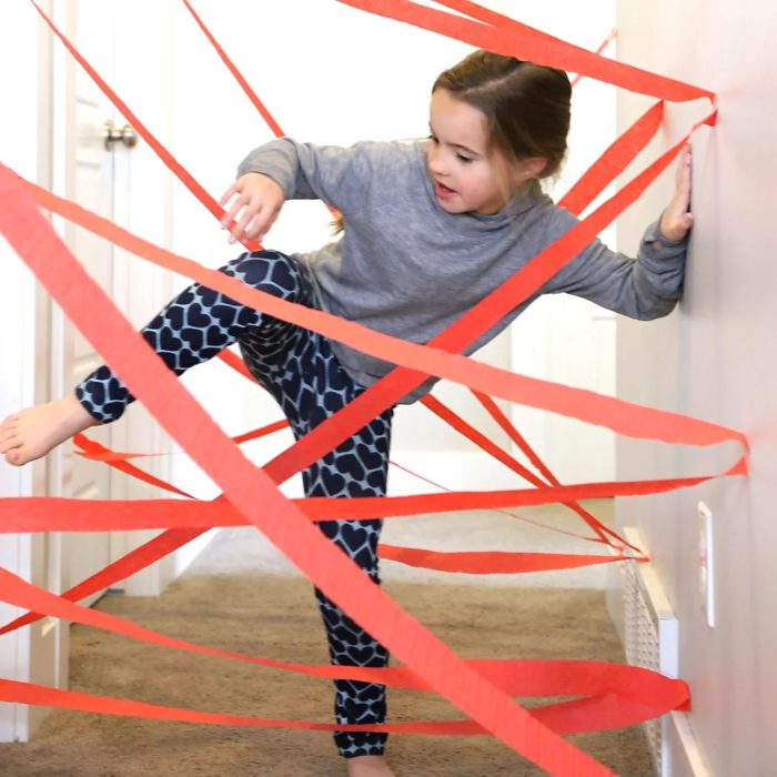Niña jugando una carrera de obstáculos en casa