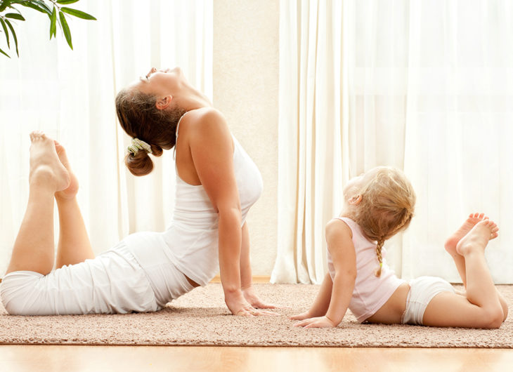 Madre e hija practicando yoga en su sala