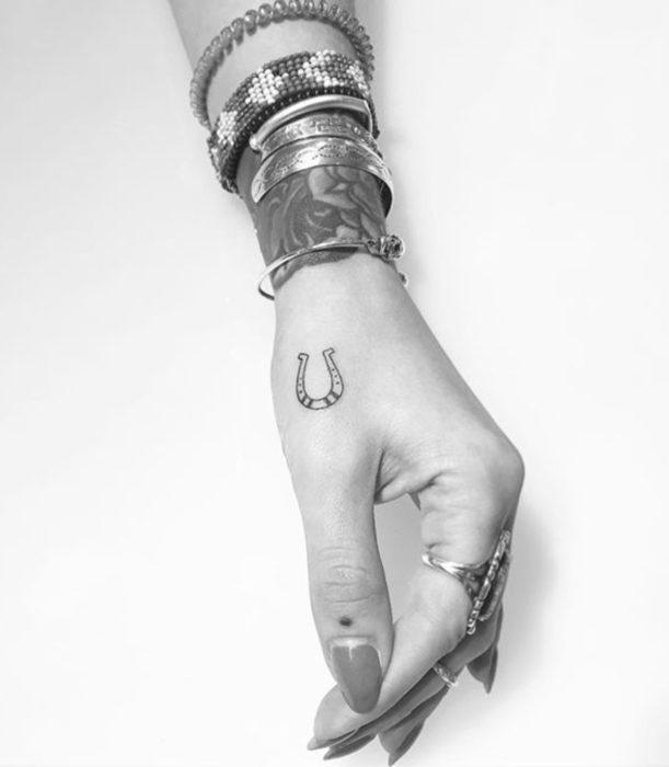 Tatuajes femeninos y discretos en las manos; herradura