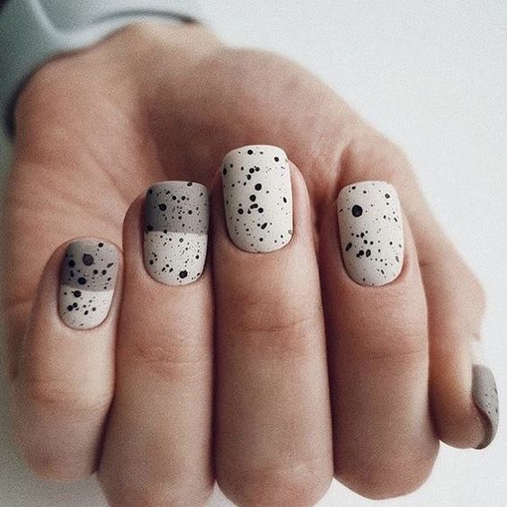 Manicura con esmalte en tono crema y gris con puntos negros