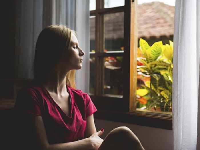 Chica meditando cerca de la ventana