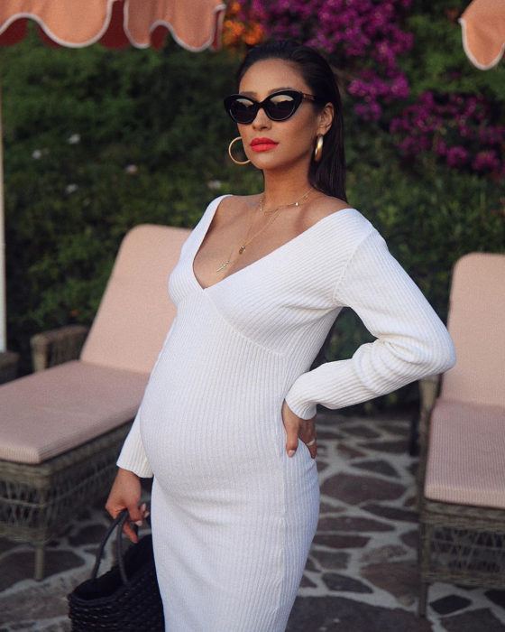 Chica embarazada usando un vestido blanco con escote profundo