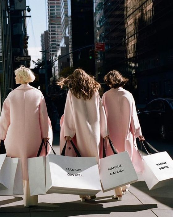 Grupo de amigas saliendo de comprar con sacos rosas pastel