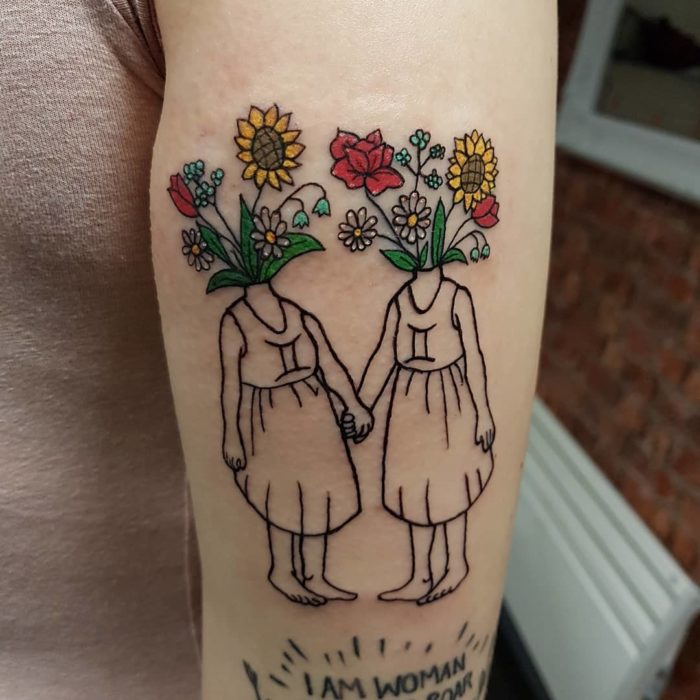 Tatuaje del signo de Géminis en tinta negra y de colores sobre el antebrazo