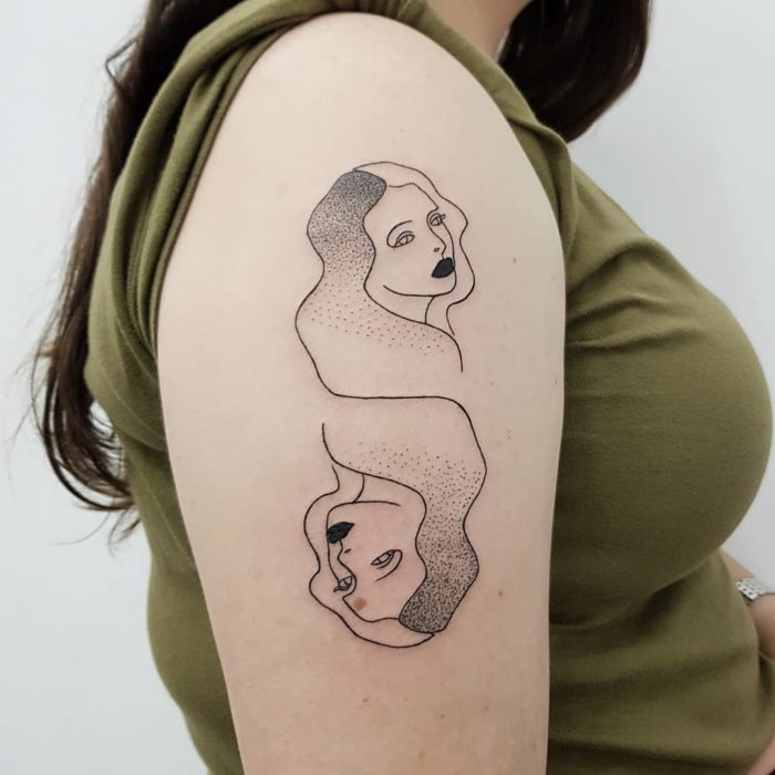 Tatuaje de Géminis en tinta negra en la parte externa del brazo