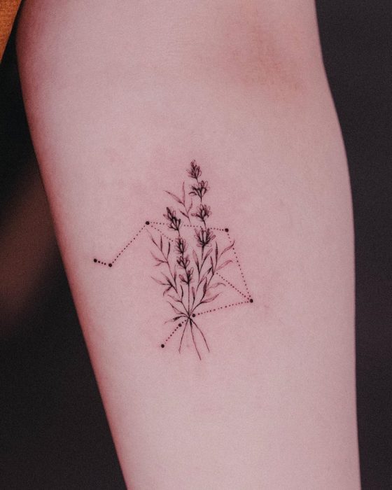 Tatuaje de la constelación de Libra adornada con vegetación en el antebrazo