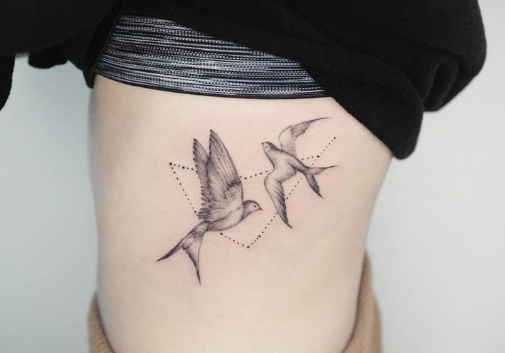 Tatuaje de la constelación de Capricornio con dos golondrinas en el lateral del abdomen