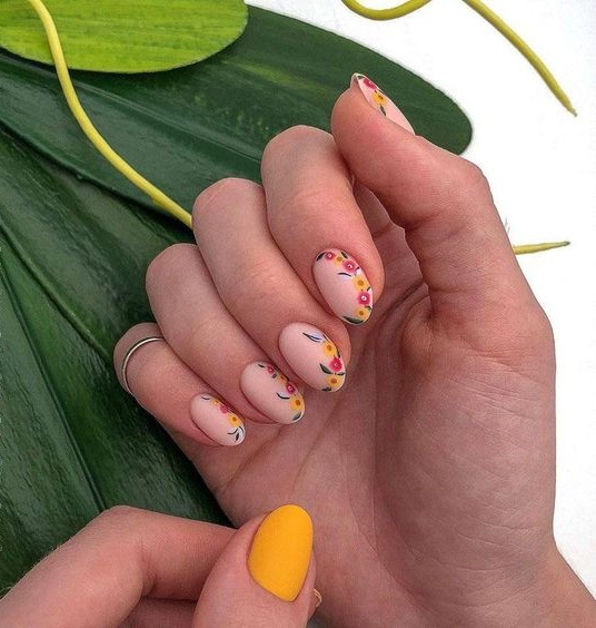 Manicura estilo francés con flores en tonos naranja, amarillo y verde