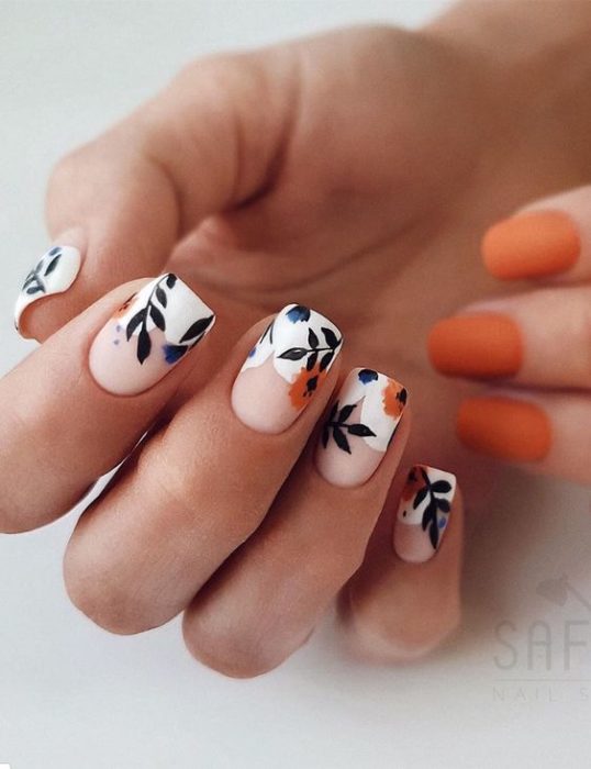 Manicura estilo francés con flores naranjas, fondo blanco y guías verdes