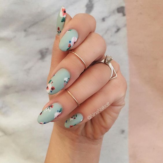 Manicura estilo francés con flores blancas sobre fondo color menta