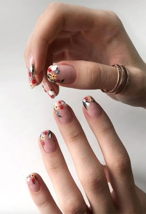 Manicura estilo francés con mini flores en tonos amarillo, naranja y verde
