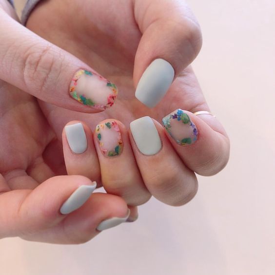 Manicura estilo francés con flores rojas y contraste con fondo azul cielo