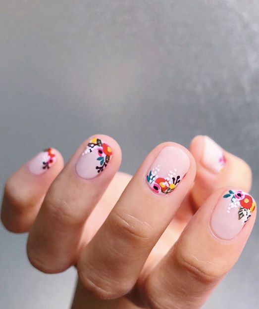 Manicura estilo francés con flores miniatura en fondo rosa pastel