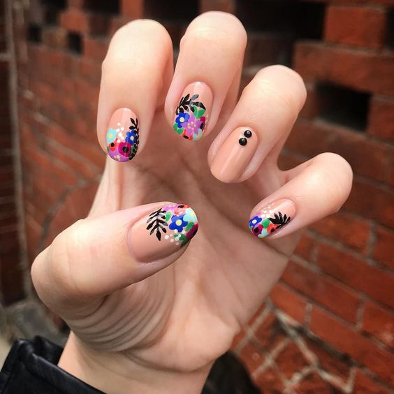 Manicura estilo francés con flores moradas, verdes, azules y rojas