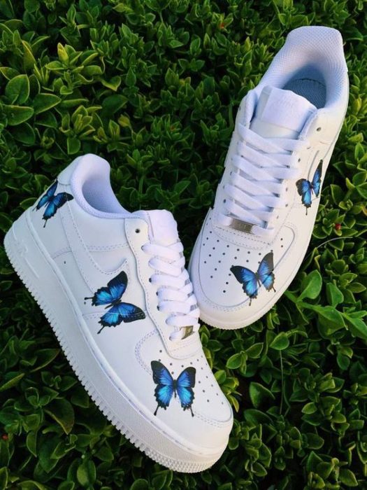 Tenis blancos con dibujos de mariposas azules a los costados