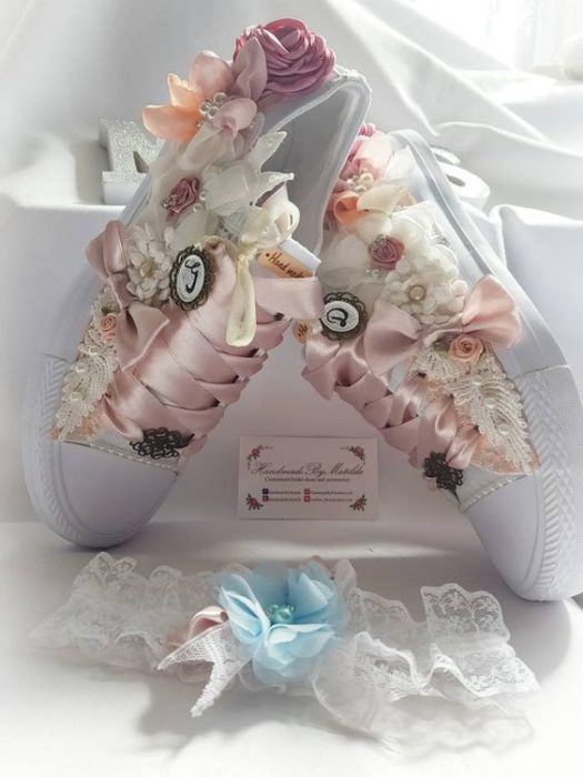 Tenis blancos con flores a los costados y cintillas de listón rosa pastel para bodas