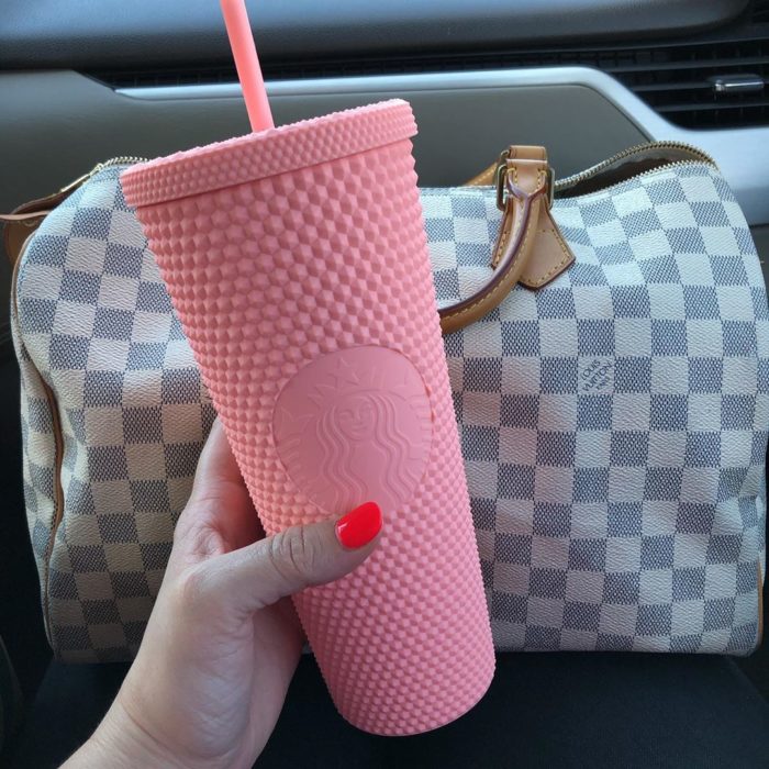Chica sosteniendo un vaso rosa de Starbucks