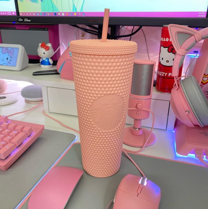 Vaso rosa de Starbucks sobre una mesa con computadoras