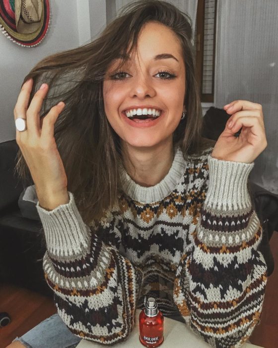 Chica sonriéndo usando suéter con cuello redondo