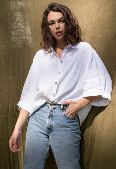 Outfit con blusa blanca; mujer castaña de cabello corto y ondulado, camisa oversized