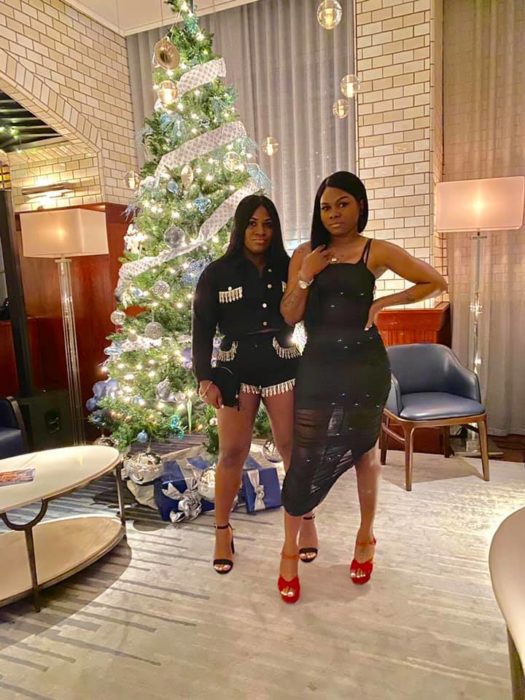 Ashley Thomas y Toya Wimberly posando frente a un pino de Navidad