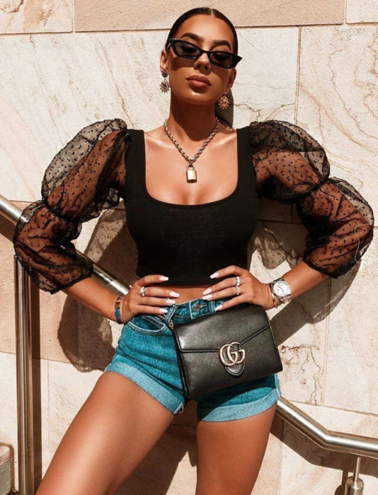 Chica morena disfrutando del sol, con lentes oscuros, top negro de encaje y short