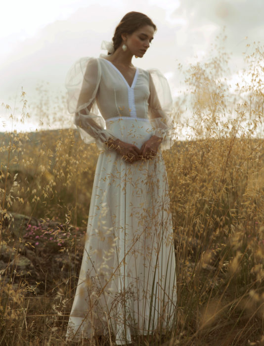 Mujer en un prado con vestido de novia marfil de mangas gigot